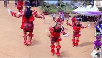 Ngbe/Ekpe masqueraders in red regalia dancing before a gathered crowd